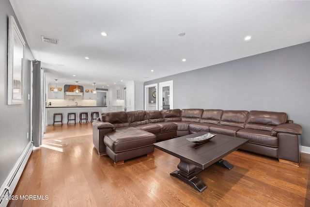 living area with visible vents, recessed lighting, baseboards, wood finished floors, and a baseboard heating unit