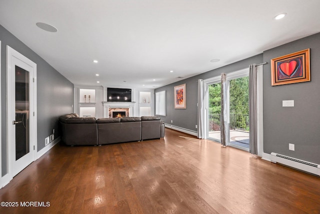 living room featuring dark wood-style flooring, baseboard heating, recessed lighting, baseboards, and a lit fireplace