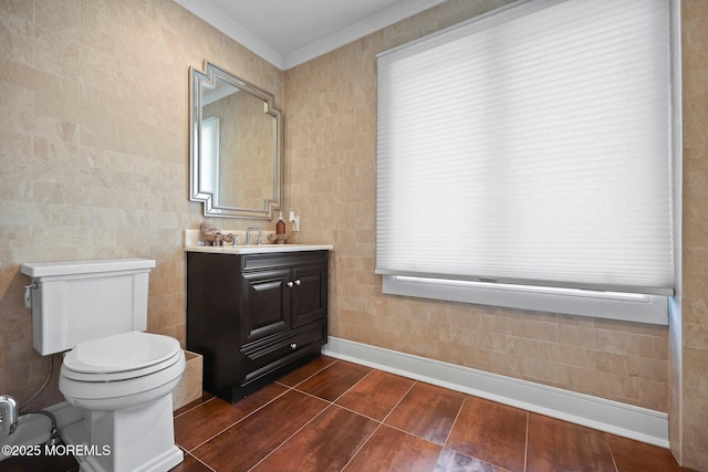 bathroom with toilet, tile walls, ornamental molding, and vanity