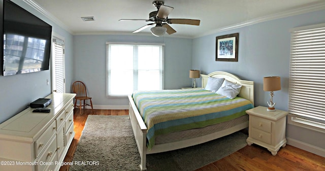 bedroom with visible vents, baseboards, crown molding, and wood finished floors