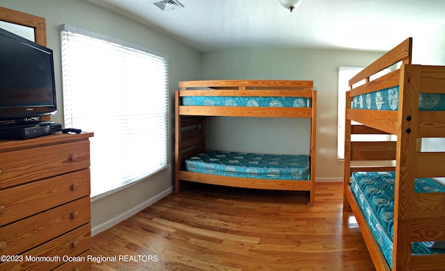 bedroom with baseboards, wood finished floors, and visible vents