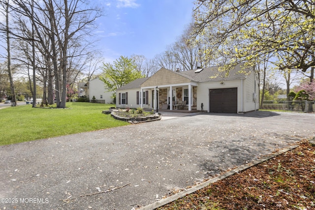 view of front facade with roof with shingles, a garage, fence, aphalt driveway, and a front lawn