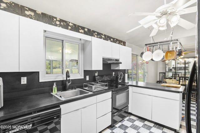 kitchen with dark countertops, light floors, under cabinet range hood, a sink, and black appliances