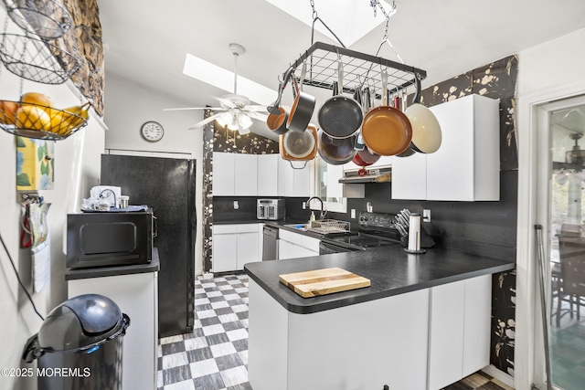 kitchen featuring dark countertops, a sink, black appliances, dark floors, and white cabinetry