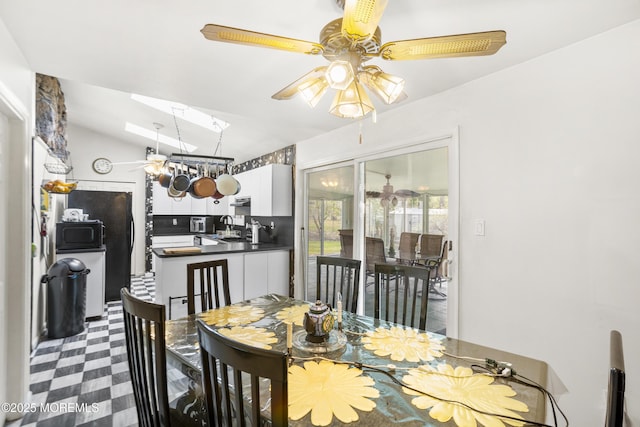 dining area featuring a ceiling fan, lofted ceiling, and dark floors