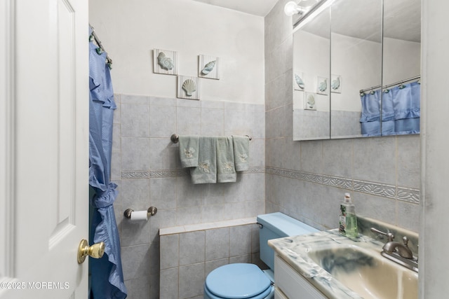 bathroom with toilet, tile walls, and vanity