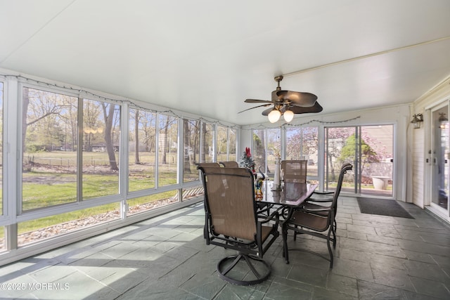 sunroom / solarium with a ceiling fan and outdoor dining space