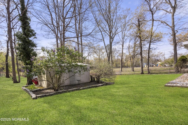 view of yard featuring a storage unit, fence, and an outbuilding