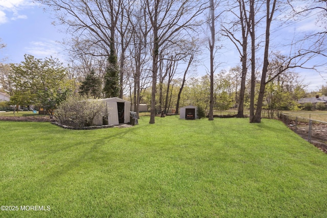 view of yard featuring an outdoor structure, a shed, and fence
