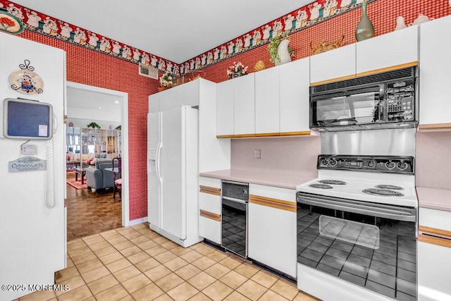 kitchen with black microwave, range with electric stovetop, white refrigerator with ice dispenser, light countertops, and white cabinets