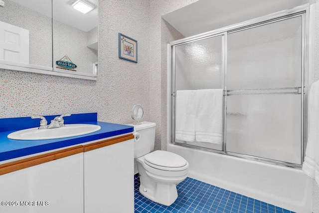 full bath featuring vanity, tile patterned flooring, combined bath / shower with glass door, and toilet