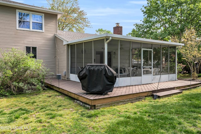 rear view of property with a shingled roof, a sunroom, a deck, a chimney, and a yard