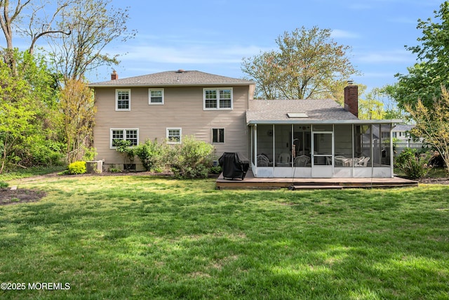 rear view of house with a lawn, roof with shingles, a chimney, and a sunroom