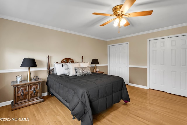 bedroom with light wood-style floors, multiple closets, crown molding, and baseboards