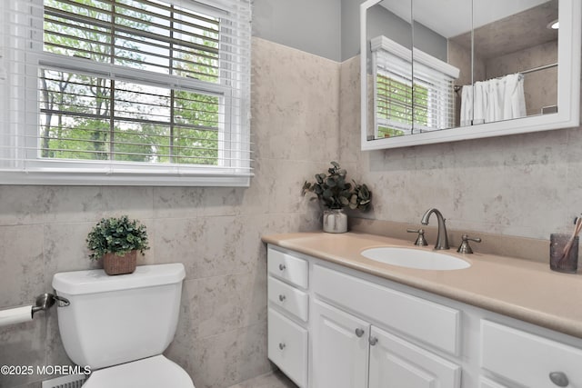 bathroom featuring a wealth of natural light, toilet, and tile walls