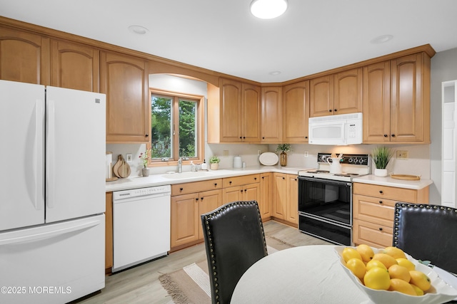 kitchen featuring white appliances, a sink, and light countertops