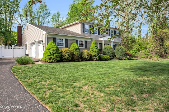 view of front of home featuring a garage, a front lawn, fence, and a gate
