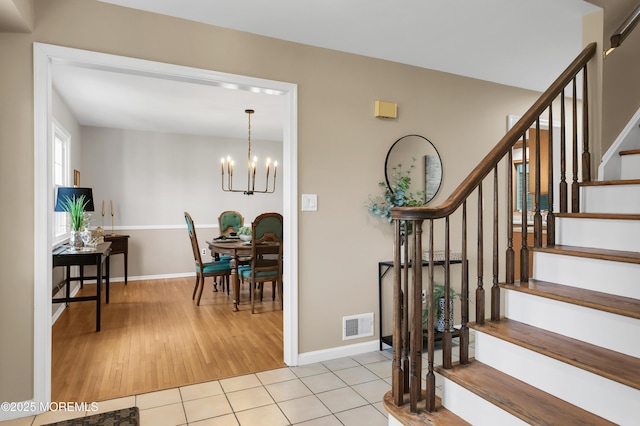 staircase with visible vents, baseboards, tile patterned floors, and a notable chandelier