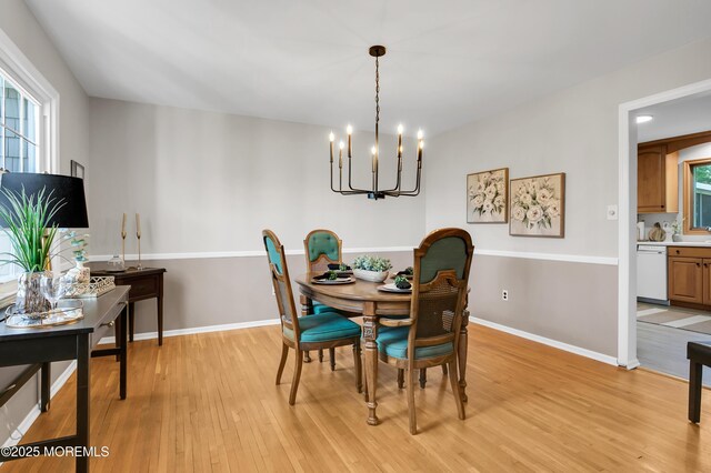 dining area featuring baseboards, an inviting chandelier, a healthy amount of sunlight, and light wood finished floors