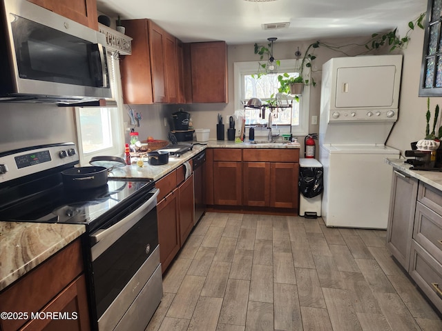517 Newtons Corner Rd, Howell, NJ 07731 - kitchen featuring appliances with stainless steel finishes, a sink, estacked washer and dryer, light wood-style flooring, and brown cabinets