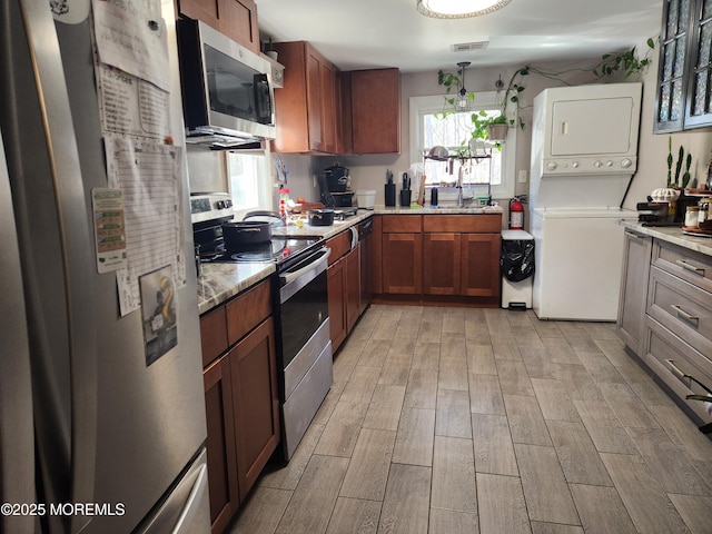 517 Newtons Corner Rd, Howell, NJ 07731 - kitchen with appliances with stainless steel finishes, stacked washer / drying machine, light wood finished floors, and plenty of natural light
