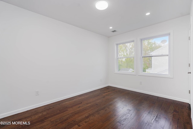 spare room featuring dark wood-type flooring, visible vents, recessed lighting, and baseboards