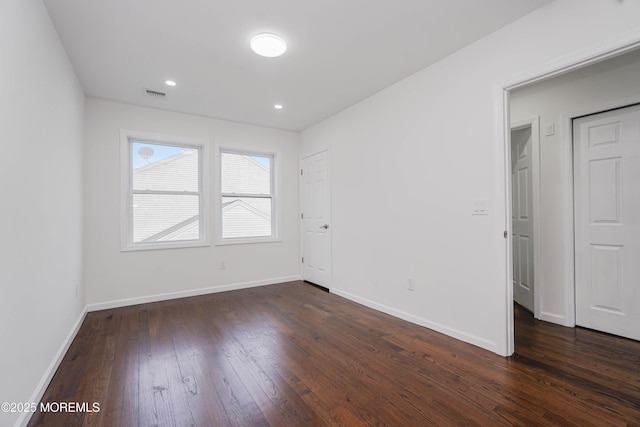 unfurnished room featuring recessed lighting, visible vents, dark wood-style flooring, and baseboards