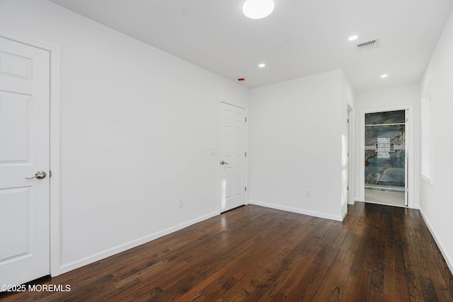 empty room with wood finished floors, visible vents, recessed lighting, and baseboards