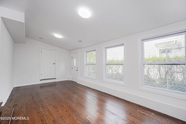 unfurnished room featuring dark wood-style floors, visible vents, lofted ceiling, and baseboards