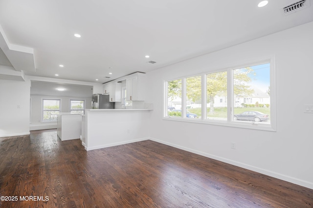 unfurnished living room with dark wood-type flooring, visible vents, recessed lighting, and baseboards