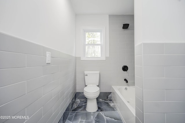 full bathroom with tile walls, wainscoting, toilet, and marble finish floor