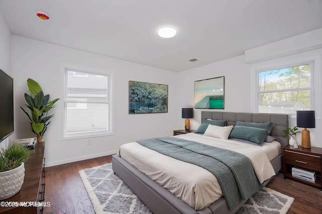 bedroom with dark wood-style flooring, visible vents, and baseboards