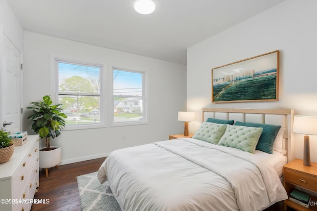 bedroom with baseboards and dark wood-type flooring