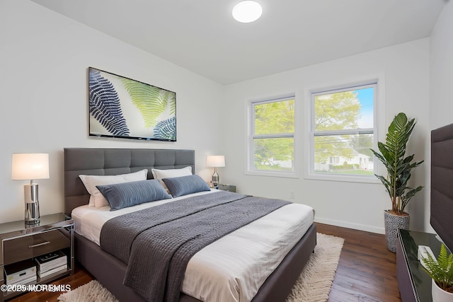 bedroom with dark wood-style flooring and baseboards