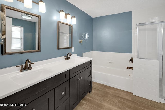 bathroom with wood finished floors, a sink, a shower with shower door, and a bath