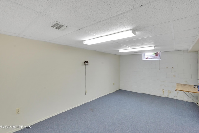 below grade area with carpet flooring, a drop ceiling, and visible vents