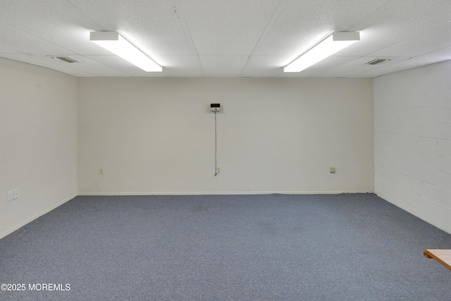 carpeted empty room with visible vents, baseboards, and a drop ceiling