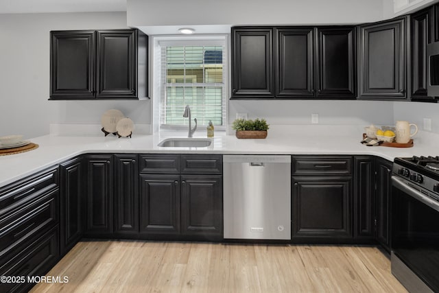 kitchen featuring a sink, appliances with stainless steel finishes, dark cabinets, and light countertops