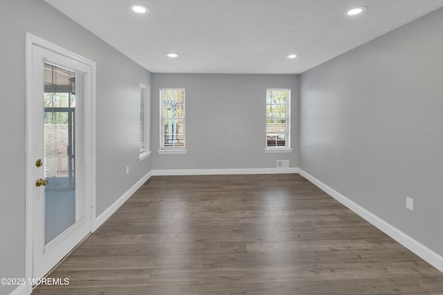 unfurnished room featuring recessed lighting, baseboards, dark wood-style floors, and a healthy amount of sunlight