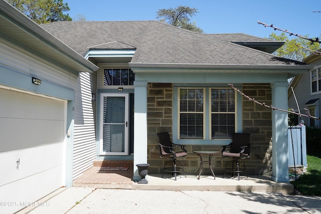 property entrance with roof with shingles, covered porch, and stone siding