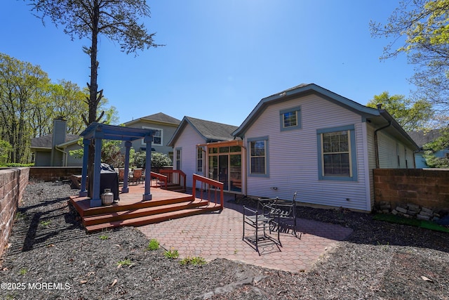 back of property with fence, a wooden deck, a patio area, and a pergola