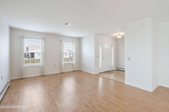 spare room featuring light wood-style floors, baseboards, baseboard heating, and visible vents
