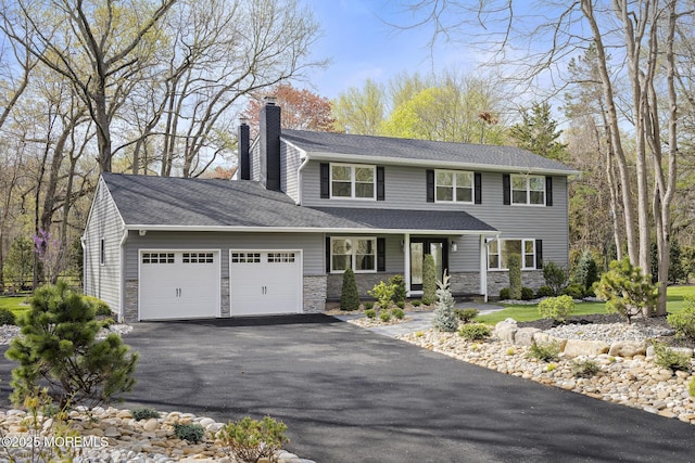 view of front facade with aphalt driveway, a chimney, stone siding, and a garage