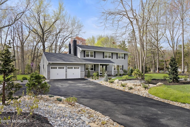 view of front of property with a garage, stone siding, a chimney, a porch, and driveway