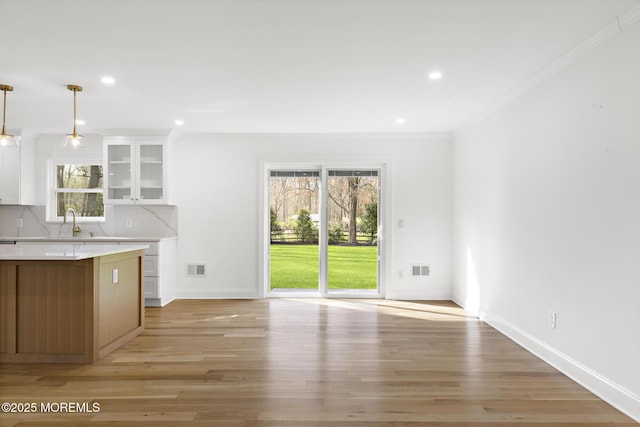 kitchen with light countertops, ornamental molding, plenty of natural light, and white cabinetry