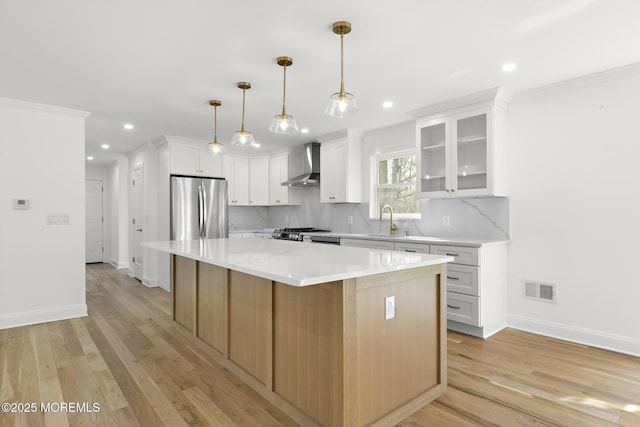 kitchen with freestanding refrigerator, light wood-style floors, wall chimney exhaust hood, tasteful backsplash, and a sink
