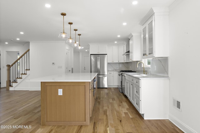 kitchen featuring decorative backsplash, a kitchen island, visible vents, a sink, and stainless steel appliances