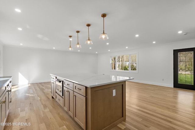 kitchen with ornamental molding, a kitchen island, and light wood-type flooring