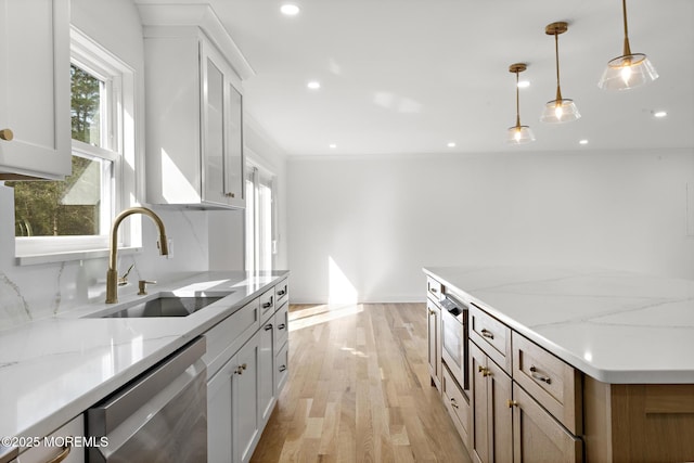 kitchen featuring hanging light fixtures, light stone counters, a sink, light wood-style flooring, and stainless steel appliances