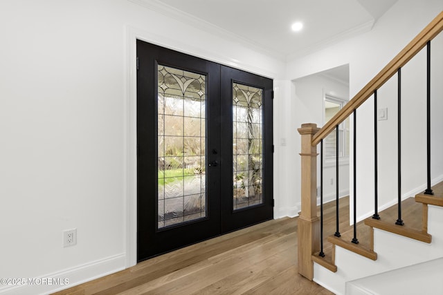 entryway featuring ornamental molding, french doors, stairway, and light wood finished floors
